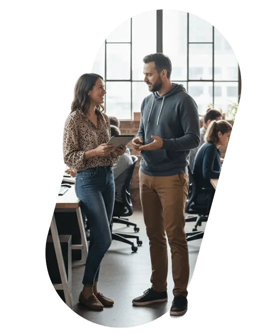Two colleagues talking over a tablet in an open-plan office