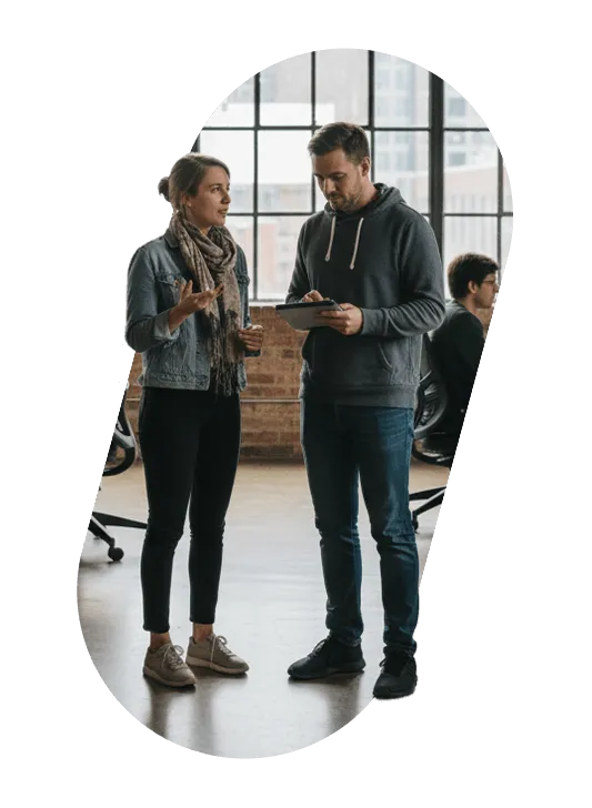 Two colleagues discussing a tablet in an open-plan office