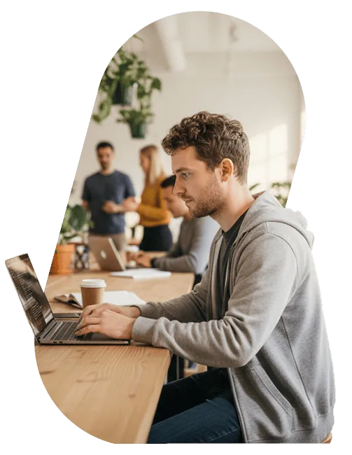 A developer coding on a laptop in a shared workspace