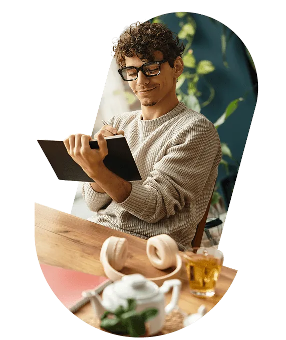A designer sketching in a notebook at a wooden table