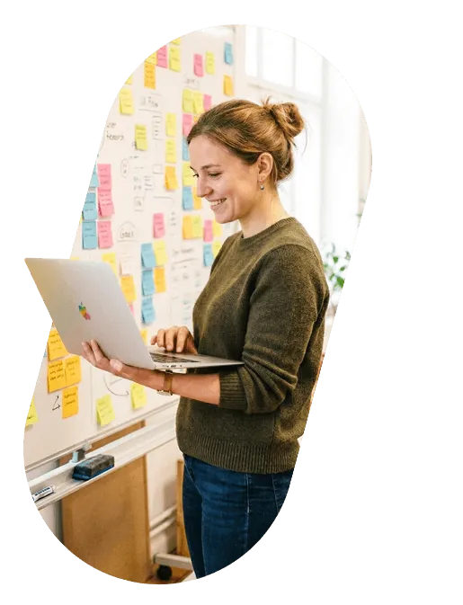 A product manager with a laptop in front of a wall of sticky notes