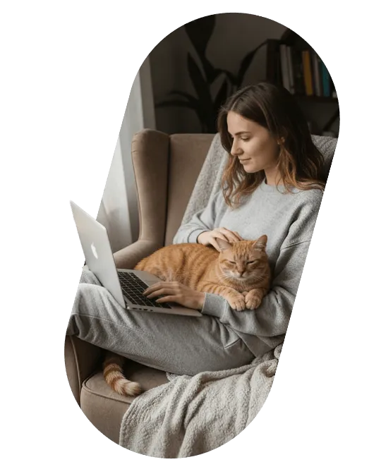 A founder reading on a laptop in an armchair, with a cat on her lap